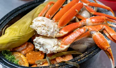 a bowl filled with crab legs, carrots and corn
