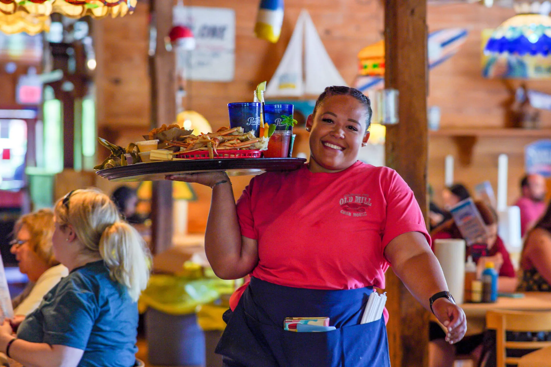 a woman carrying a tray of food in a restaurant