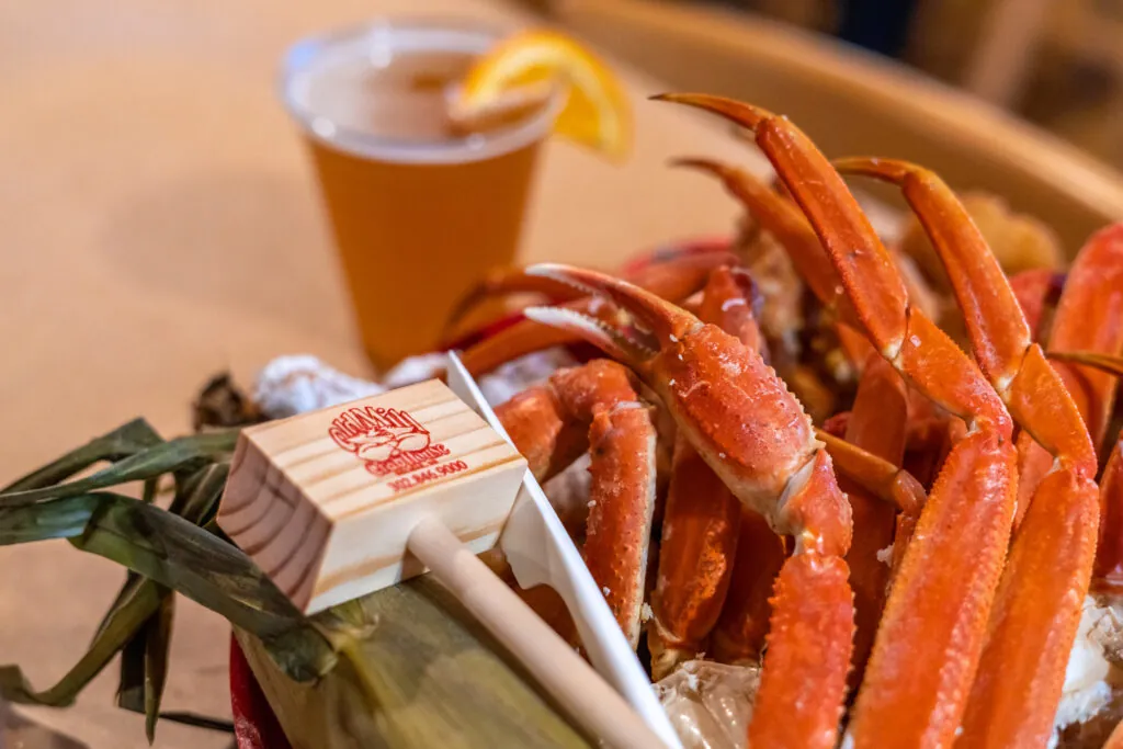 a basket filled with lots of crab legs next to a cup of beer