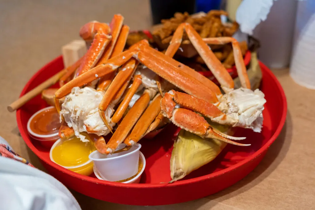 a plate with crab legs and dipping sauces